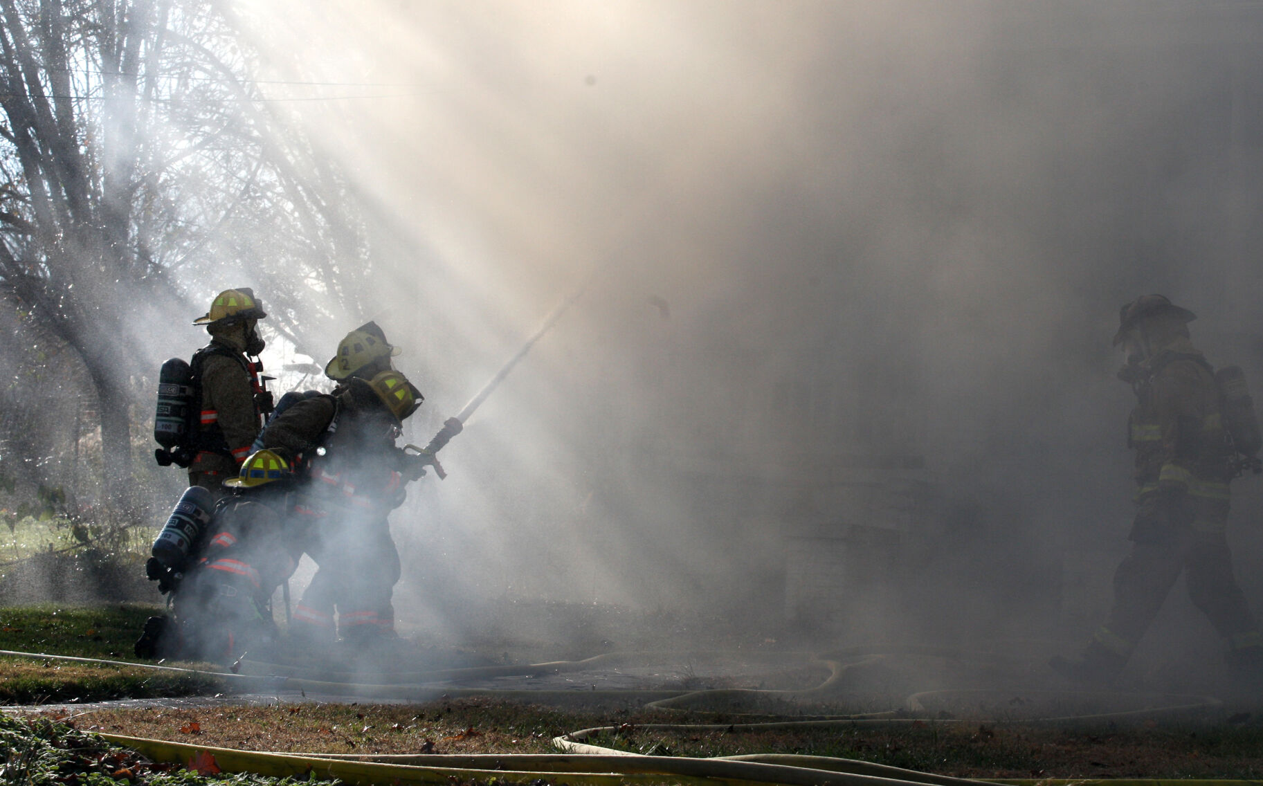 Firefighters aim hose through smoke